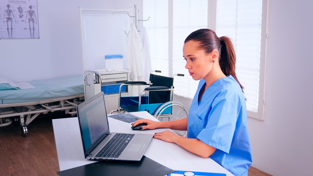 Nurse updating patient details in the medical coding systems using the laptop